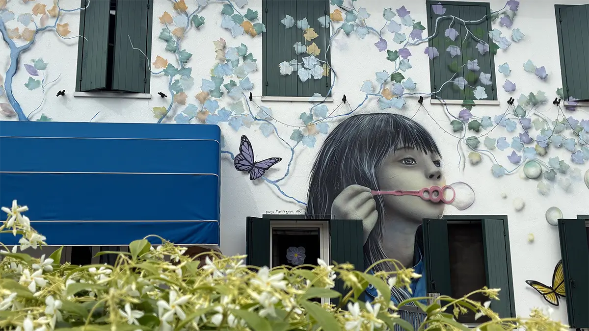 Murale di una bambina che soffia bolle su una facciata a Brugnera.