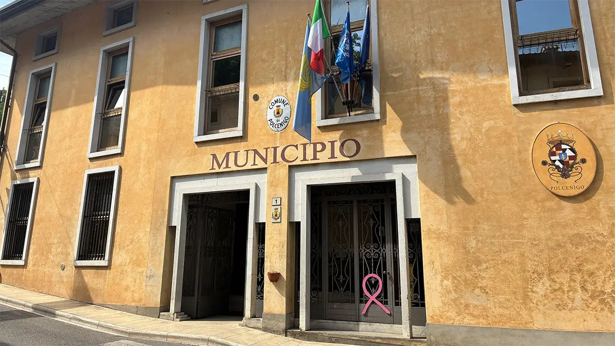 Facciata del municipio di Polcenigo con bandiere e stemma comunale.